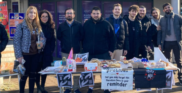 Members of the Turkish Society standing behind a table selling cakes to fundraise