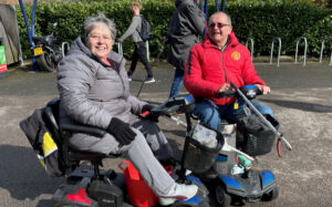 Clive and Sheila Payne on mobility scooters with litter-picks on Whiteknights campus