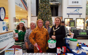 Sarah as Mayor standing with other people at a fundraising stand.