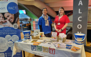 Sarah and a colleague in front of a PACT information stand.