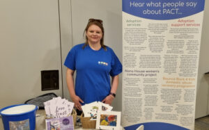 Sarah standing in front of a PACT information stand.