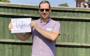 Steve Hendry holding up a sign saying 'We'