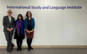 Bruce, Laura and Leslie standing in front of a sign that says 'International Study and Language Institute'.