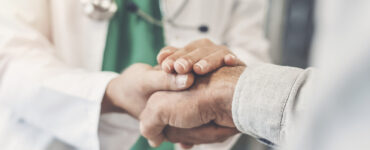 Hospital worker holding a patient's hand