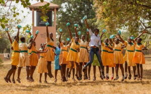 Mabel and a group of girls jumping in the air holding packs of sanitary pads