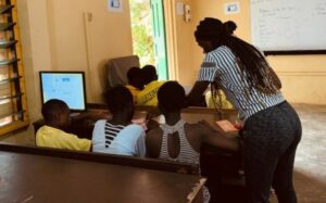 A teacher teaching girls on a computer in Ghana