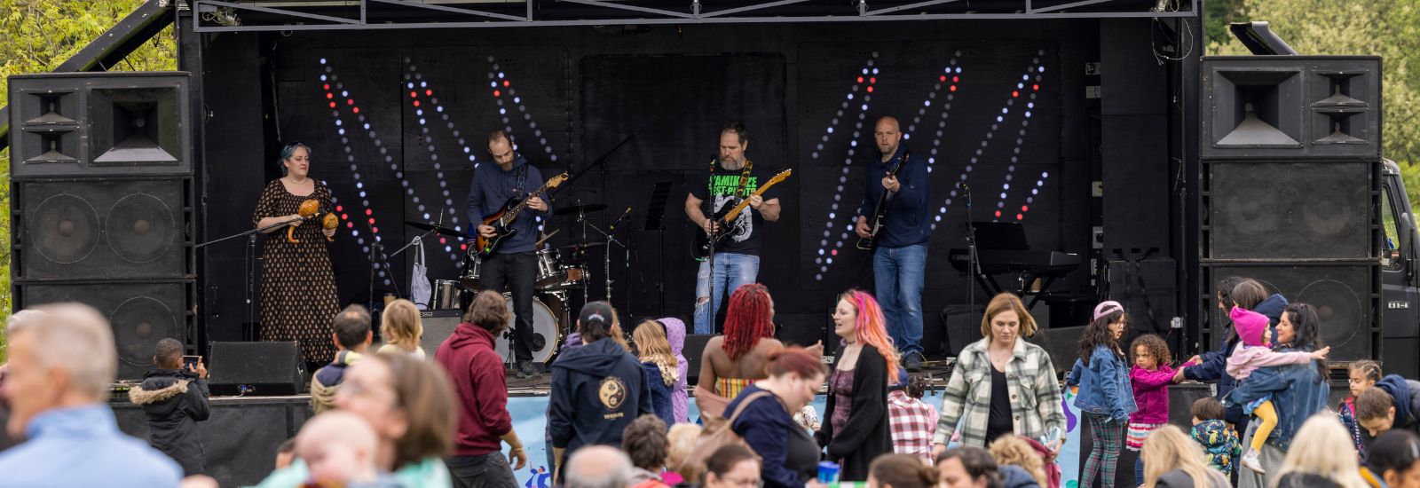 A band performing at the Community Festival while a crowd watches