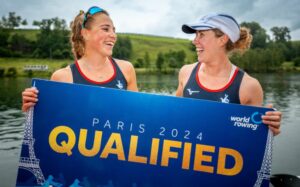 Mathilda Hodgkins-Byrne with her rowing partner, Rebecca Wilde, holding up a sign that says Paris 2024 Qualified.