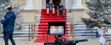 A film set showing a camera and two actors sat on steps