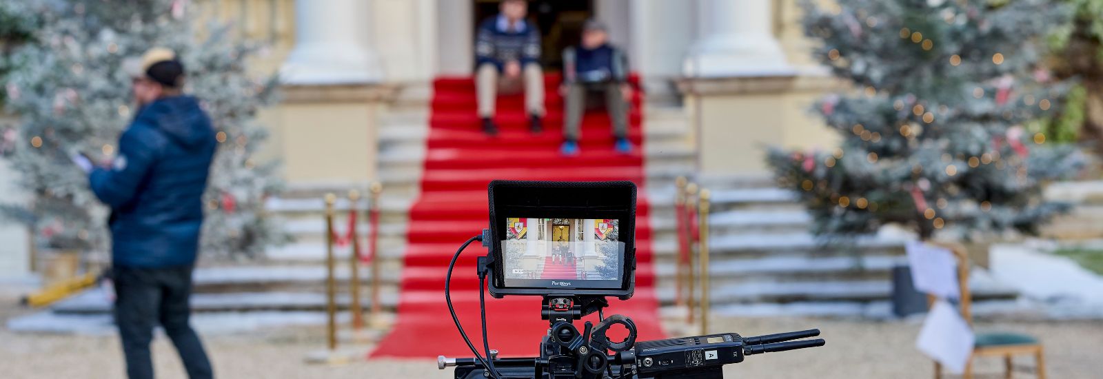 A film set showing a camera and two actors sat on steps