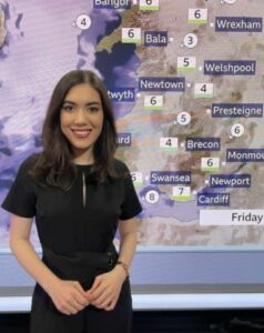 Sabrina standing in front of a weather map