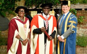 Victor smiling with University staff members at his honorary degree ceremony