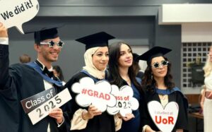 Graduates posing at graduation with photo signs