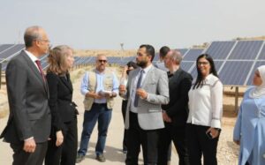 Feras talking to people in front of solar panels in Jordan