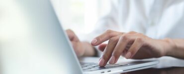 A lady's hands typing on a laptop