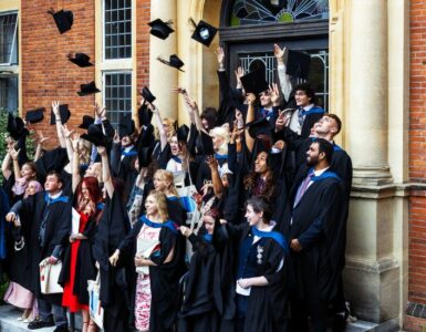 Students throwing their caps in the air at graduation on the London Road Campus steps