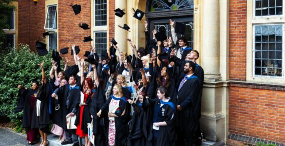 Students throwing their caps in the air at graduation on the London Road Campus steps