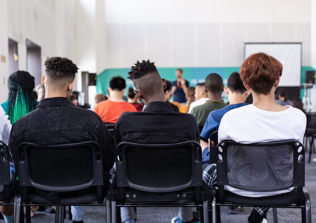 Men sitting on chairs with back to camera