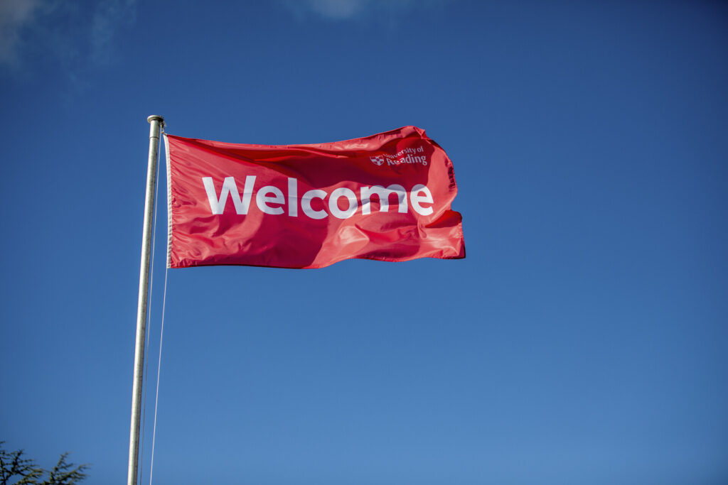 red welcome flag flying on a flagpole 