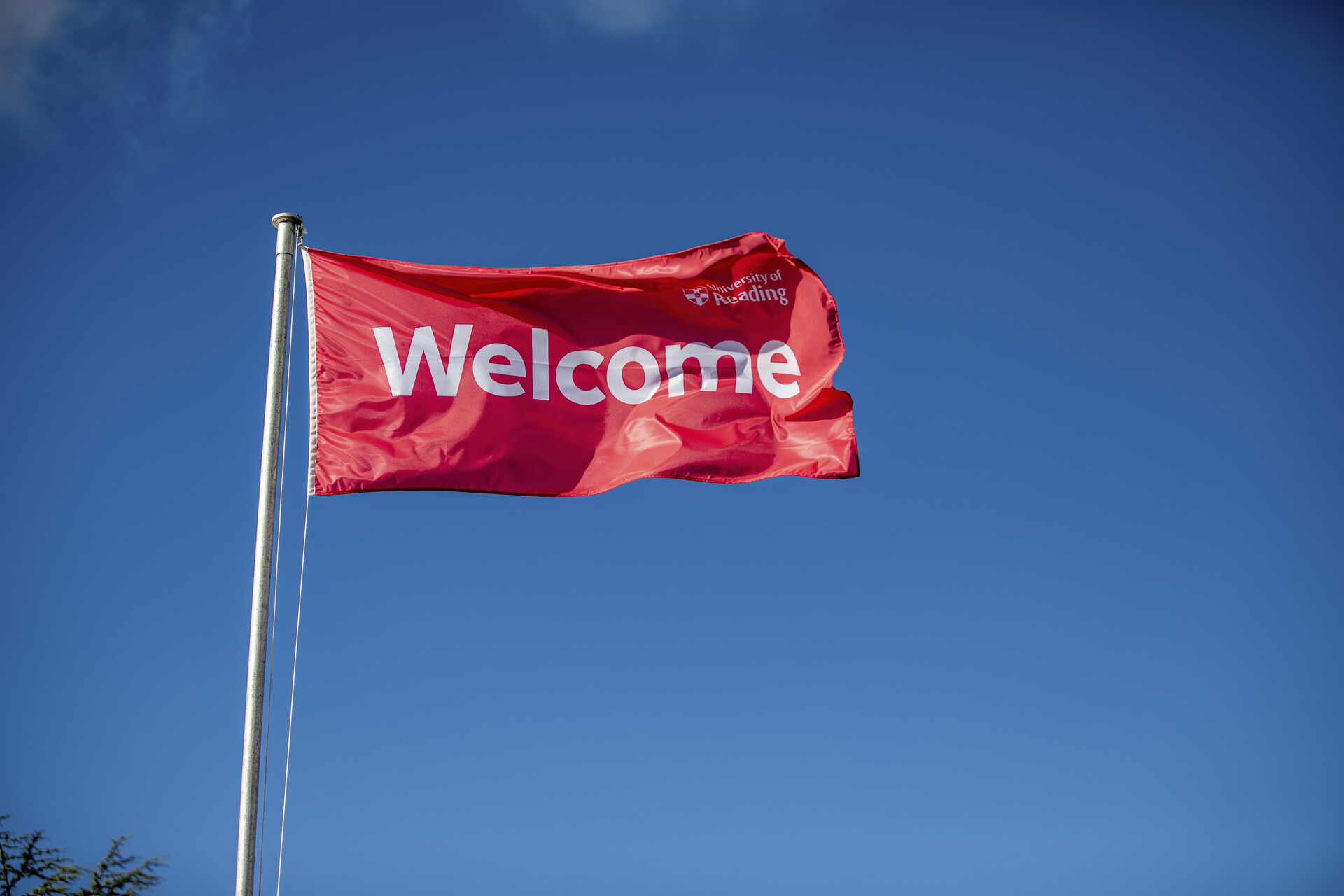 red welcome flag flying on a flagpole