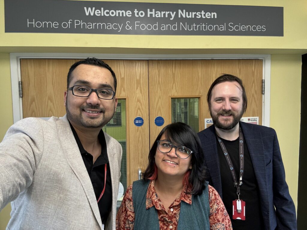 Three people standing in front of doors with a sign above them that says "Welcome to Harry Nursten Home of Pharmacy & Food and Nutritional Sciences."