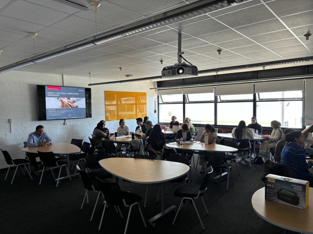 Students in a classroom working in groups; a slide titled 'PRIVILEGE AND OPPRESSION' is displayed