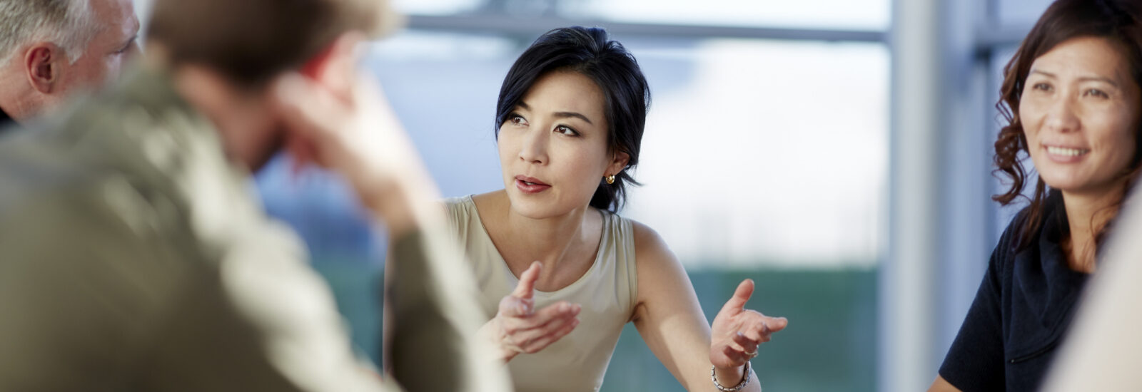 Women speaking to men in a business meeting