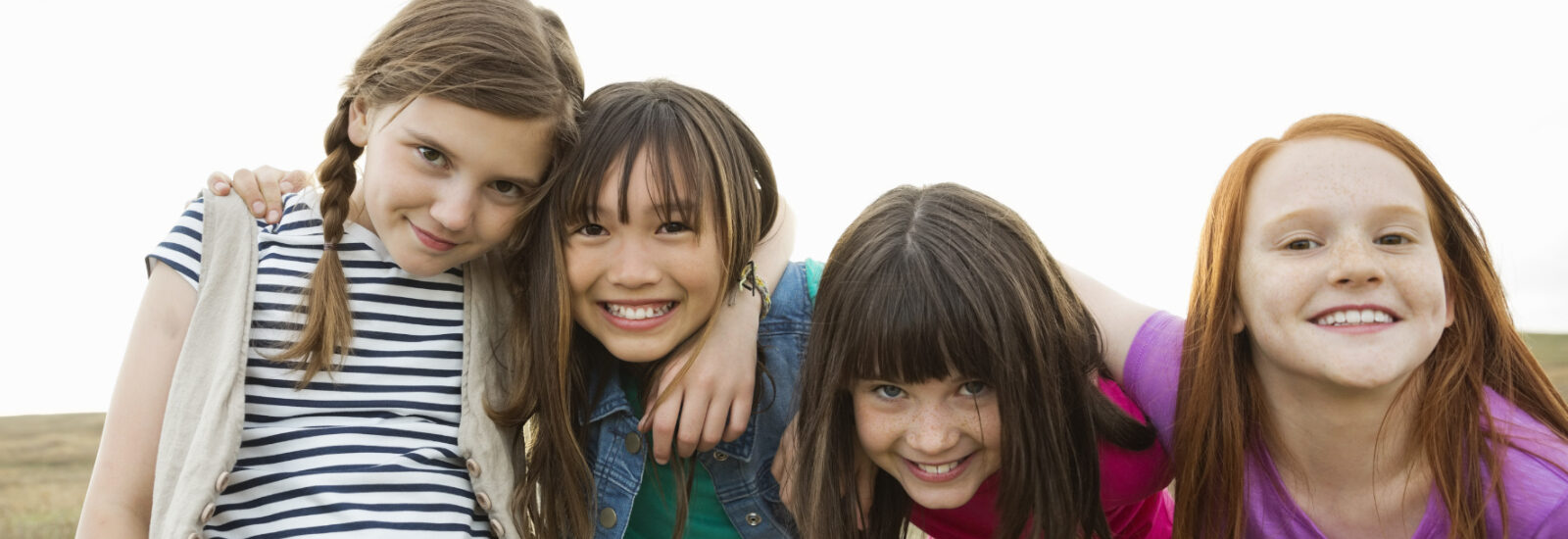 Group of 4 girls hugging and smiling at the camera
