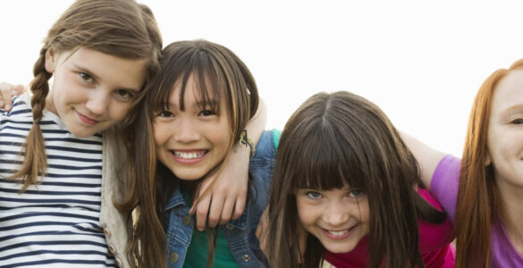 Group of 4 girls hugging and smiling at the camera
