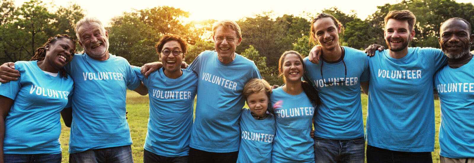 Group of volunteers standing in a line with arms around each other.