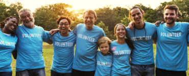 Group of volunteers standing in a line with arms around each other.