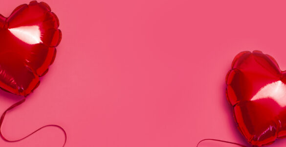 Red love heart balloons on a pink background