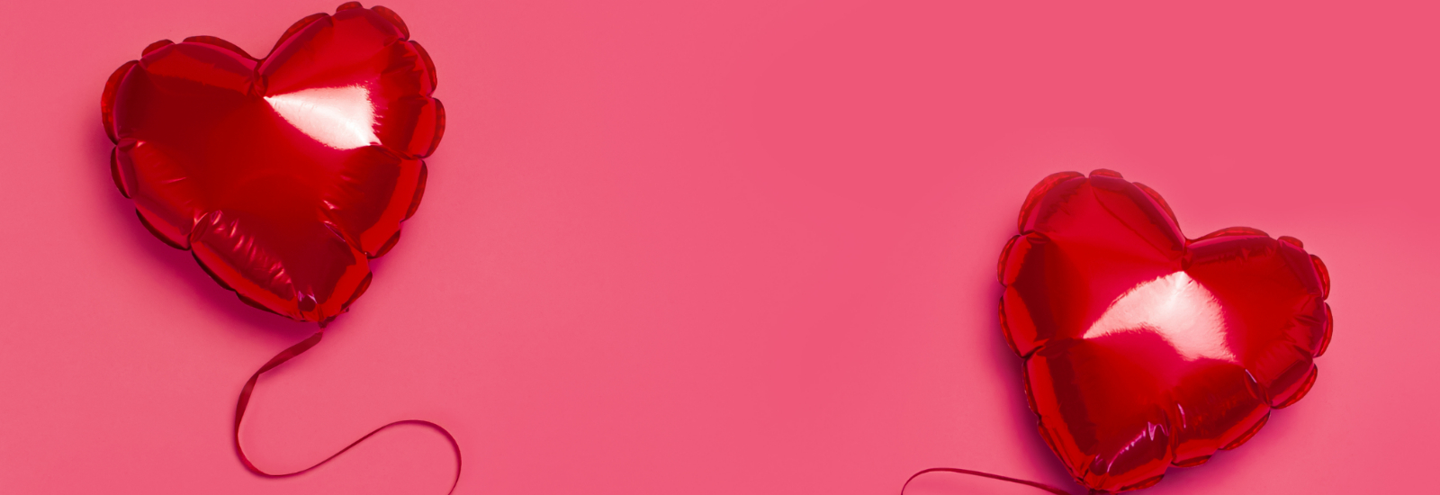Red love heart balloons on a pink background