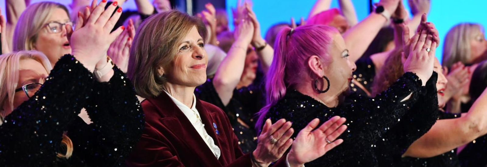 Stella in a crowd of women clapping.