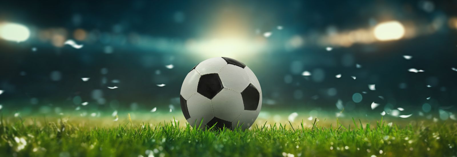 Football in the centre of a stadium pitch with confetti falling