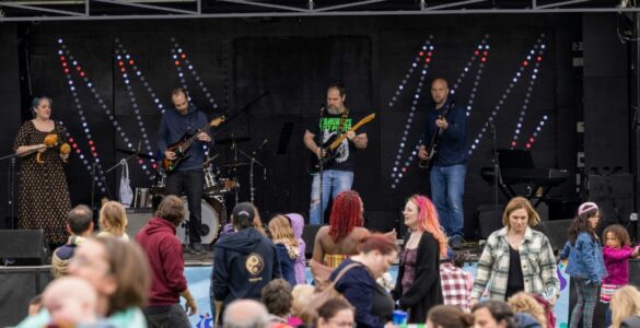A band performing at the Community Festival while a crowd watches