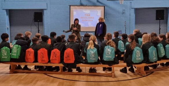 Group of school children sitting on a bench wearing resilience rucksacks
