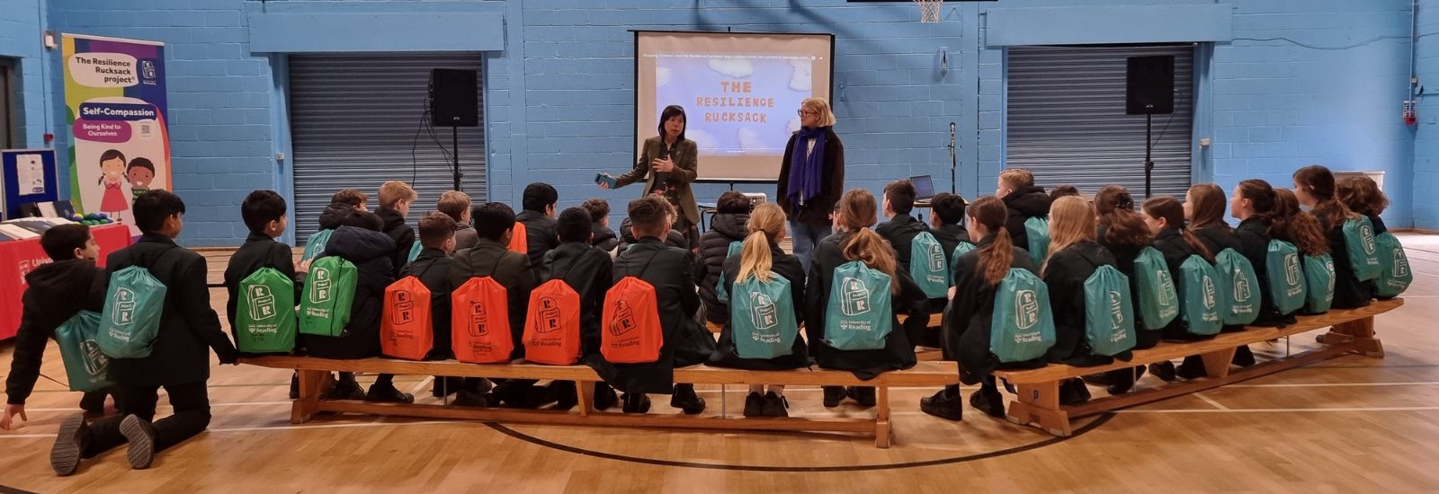 Group of school children sitting on a bench wearing resilience rucksacks