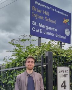 Serhan Wade standing in front of a school sign