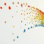 An abstract picture of multi-coloured beads on white paper.