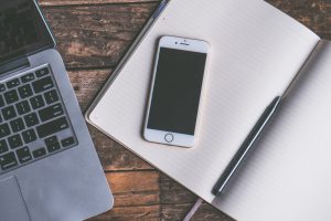 A picture of a phone and laptop with blank screens in a study environment.